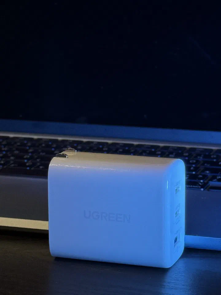 綠聯 CD275 65W 充電器立放在 MacBook 鍵盤前的情境照